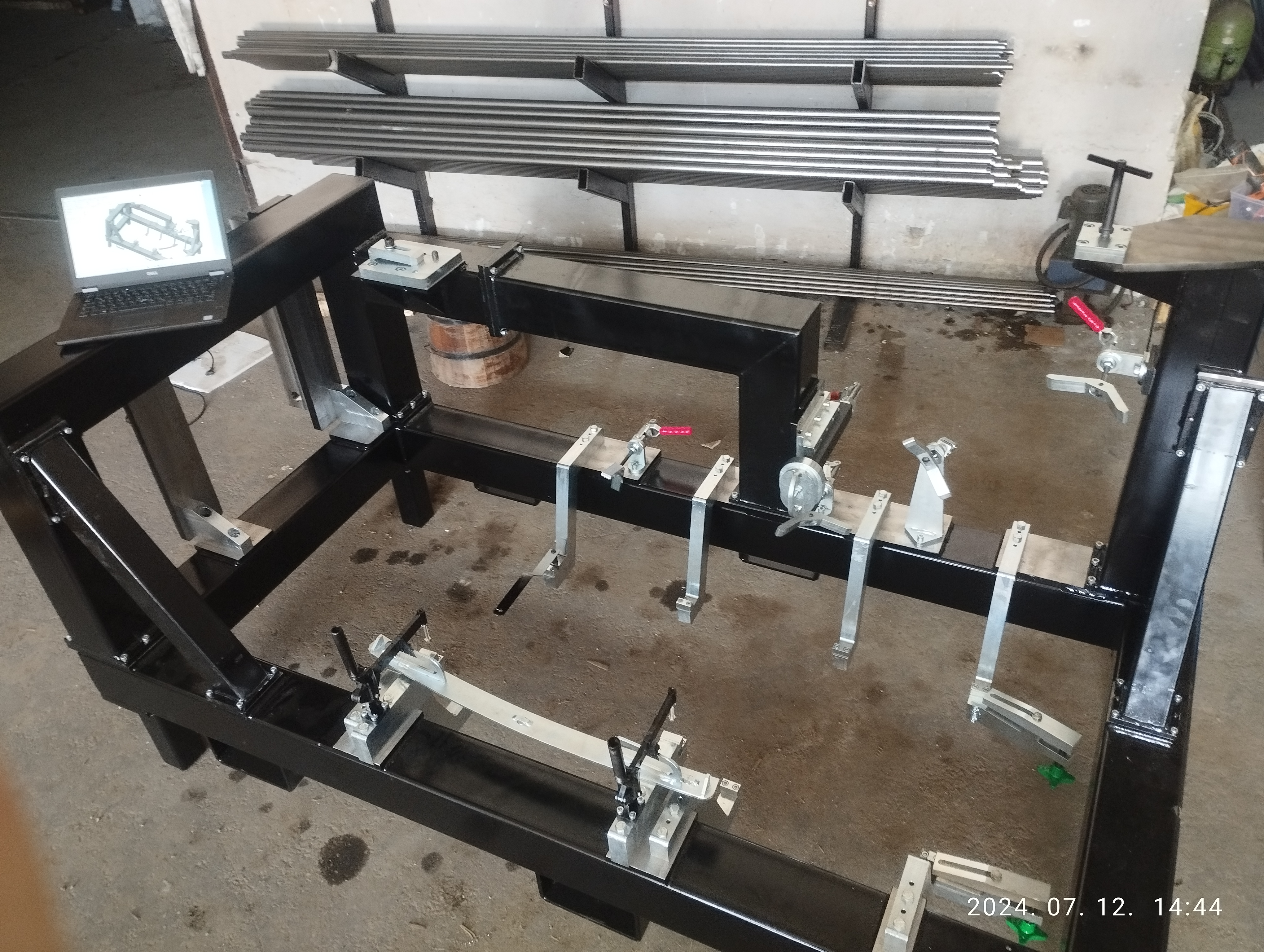 Hegesztőkészülék a műhelyben, mellette a számítógépen látható 3D modell
